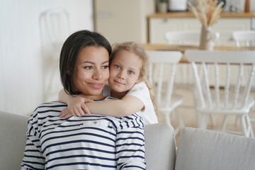 Blonde cute little girl hugs mom. Young spanish mother and european kid. Child adoption concept.