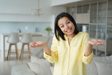 Cute happy puzzled woman, dont know concept. Confused girl in living room at home.