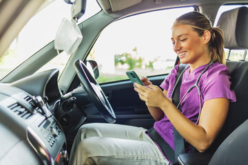 Nurse arriving at a patient's home, she is sitting in her car using her mobile phone. A nurse...