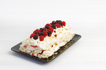 Homemade delicious meringue dessert with berries on white wooden table.