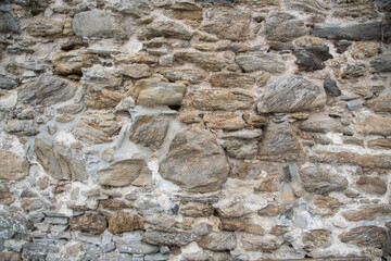 House wall with quarry stones whitely plastered, natural stone texture for horticulture and garden design, close up