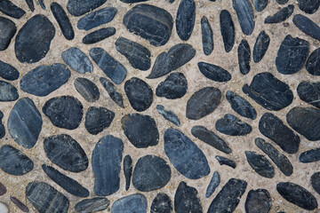 Paved walkway with small black natural stone pebbles filled with sand - roadbuilding, modern garden...
