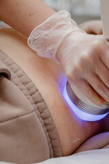 A woman in a beauty salon receives a vacuum abdominal massage, Hardware cosmetology.