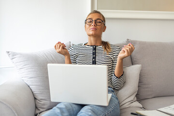 Shot of a young businesswoman meditating while using a laptop. Woman meditating sit at desk in...