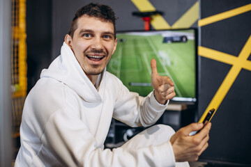 Man watching football and using mobile phone