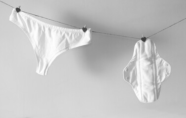 Reusable pad and women's panties dry on a rope. Black and white photo.