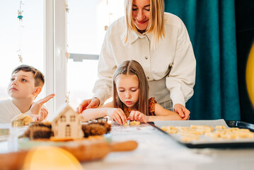 Happy kids cooking cookies bakery together and having fun with flour indoors at cozy home on the kitchen table. Siblings in big loving family