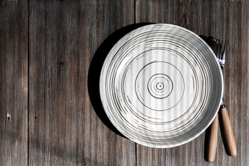 Empty ceramic white plate on a rustic loft wooden table. Kitchen food background with copy space with mockup for menu or recipe top view