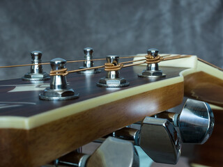 Fototapeta na wymiar Acoustic guitar head with chrome shelves and stretched strings. Close-up.