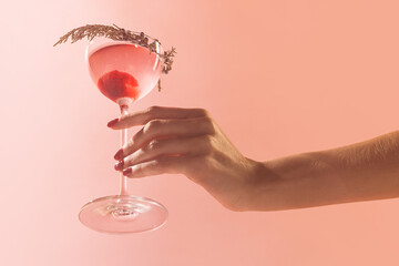 Glass of delicious alcohol drink with berries, cosmopolitan cocktail isolated over peach background