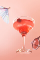 Glass of delicious alcohol drink, strawberry margarita cocktail isolated over pink background. Summer