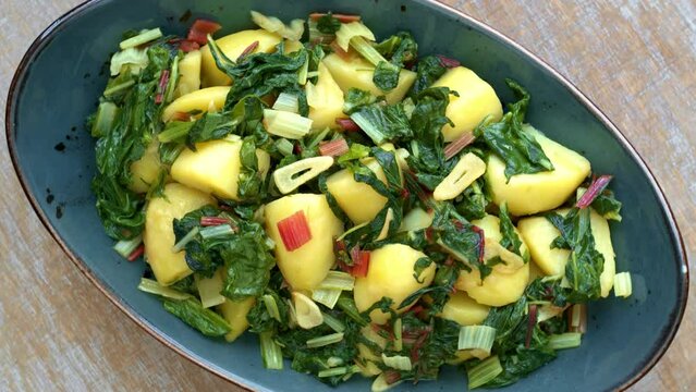 Potatoes with swiss chard leaves. South Croatian Blitva dish made with boiled potatoes, swiss chard, garlic and olive oil. Table spin.
