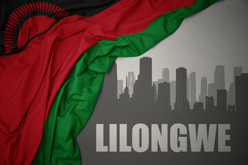 abstract silhouette of the city with text Lilongwe near waving colorful national flag of malawi on a gray background.