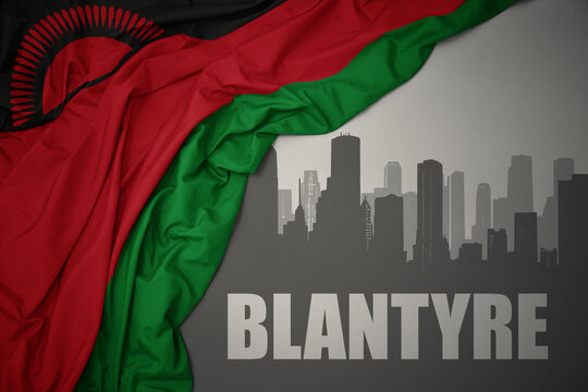 abstract silhouette of the city with text Blantyre near waving colorful national flag of malawi on a gray background.