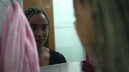 One confident black latina woman looking at herself in front of mirror