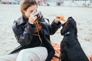 Young woman taking picture of her dog with vintage film camera