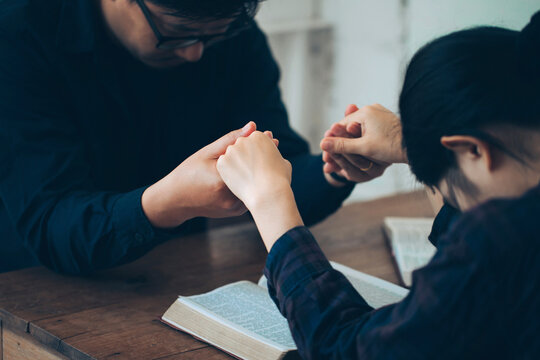 Christian Family Worship Holding Hands Together And Prayer On The Holy Bible.Christian Holding Hand And Praying. Devotional For Prayer Meeting Concept.Begging For Forgiveness And Believing In Goodness