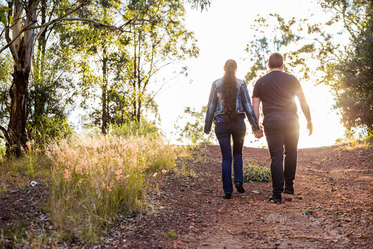 Couple walk up hill hand in hand along track