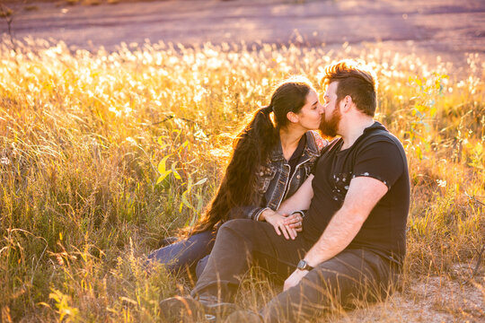 Married couple sit together in paddock and share a kiss