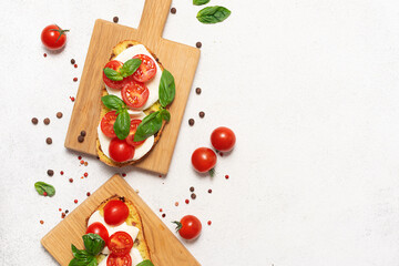 Juicy aromatic caprese sandwiches with basil leaves, cherry tomatoes and mozzarella cheese on the wooden cutting boards on white background top view. Healthy tasty food concept.