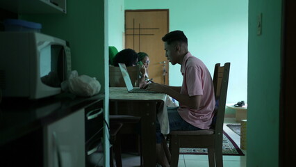 Candid young man browsing internet in front of laptop computer at home living room