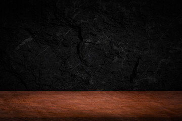 Empty space on wooden table for displaying food or beverage products with blurred black wall...