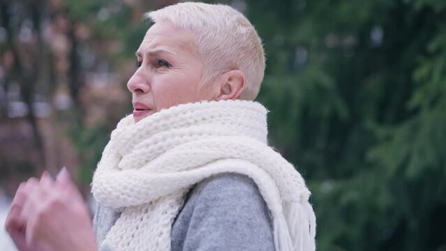 Middle-aged woman waiting on a blind date in cold winter park, trying to warm up