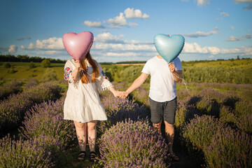 Happy couple holding surprise balloon during gender reveal party in lavender field. 