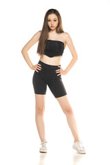 Young woman in black shorts and top posing in the studio on white background