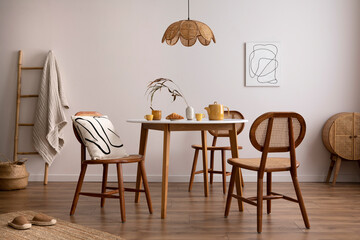 The stylish dining room with round table, rattan chair, wooden commode, poster and kitchen...