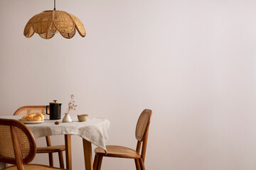 The stylish dining room with copy space, round table, rattan chair, lamp and kitchen accessories....