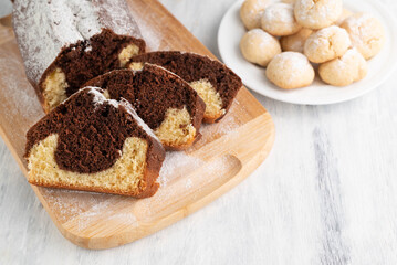 Blurred image of cookies in a plate and a cupcake on a cutting board on a light table. The concept of home baking.