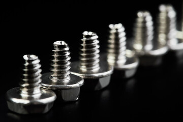 A row of Small bolts for computer equipment and computer assembly on black background