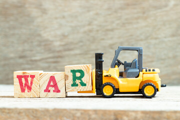 Toy forklift hold letter block R to complete word war on wood background