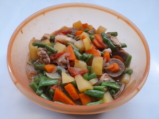 Vegetable soup consisting of carrot, potato, chickpeas, meatball slices in a bowl on a white background. healthy food concept, vegetarian, diet, cuisine, meal, breakfast, lunch, food recipe, lifestyle