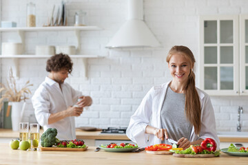 Happy couple cooking in the kitchen salad together, preparing food in home