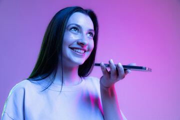 Half-length shot of emotional girl with long glossy dark hair isolated on purple background in neon light. Concept of beauty, art, fashion, emotions