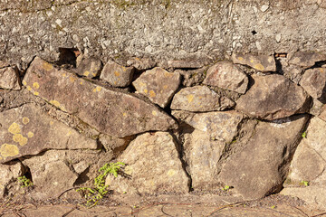 Hedge of irregular stones. Stone wall with concrete.