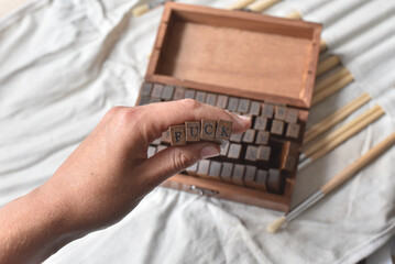 Wooden typography stamp letters spelling Fuck