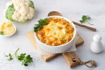 Homemade cauliflower casserole with cheese on a light gray background with ingredients. Delicious vegetarian food - 518321419