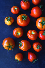 Fresh organic tomatoes, picked from the garden, on dark background. Flat lay.