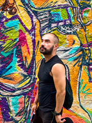 Obraz na płótnie Canvas Hombre mirando arriba en barrio lleno de arte urbano