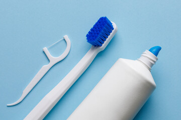 White toothbrush with toothpaste and dental floss on a blue background