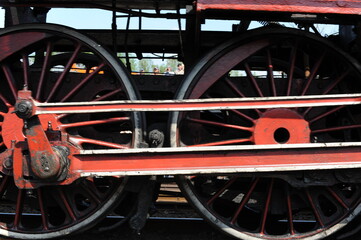 Red and black iron wheels of a running old steam locomotive