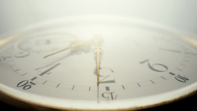 Antique pocket watch with a white dial and gold moving hands is spinning in bright light. The face of an old clock with numbers extra close up. Round mechanical vintage pocket watch.