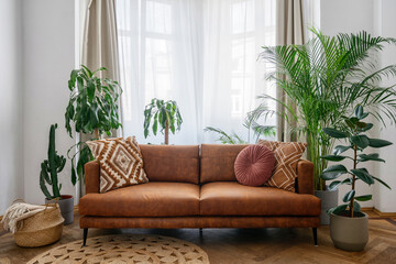 Brown sofa, potted green plants and wicker basket in room