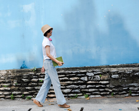 Woman wearing white shirt and blue jeans walking with happy feeling