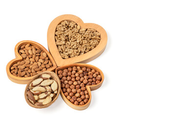 Variety of nuts in wooden cups in the shape of a heart isolated on a white background. Copy space.