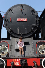 A young boy standing in front of a steam locomotive train