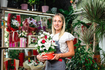 Beautiful blonde florist girl holding flowers in her hands at her flower shop. Self employed, small business concept